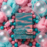 Two rectangular bars of soap stacked in the center, one smooth and one textured, embossed with the brand name 'LUNARAYA'. The soaps are a teal-blue color with pink marbled swirls.